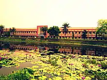Long, low building across a pond with water lilies
